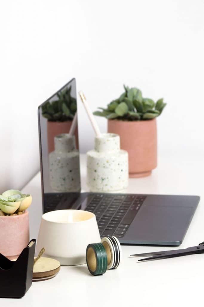 laptop computer with candle and plant on office desk