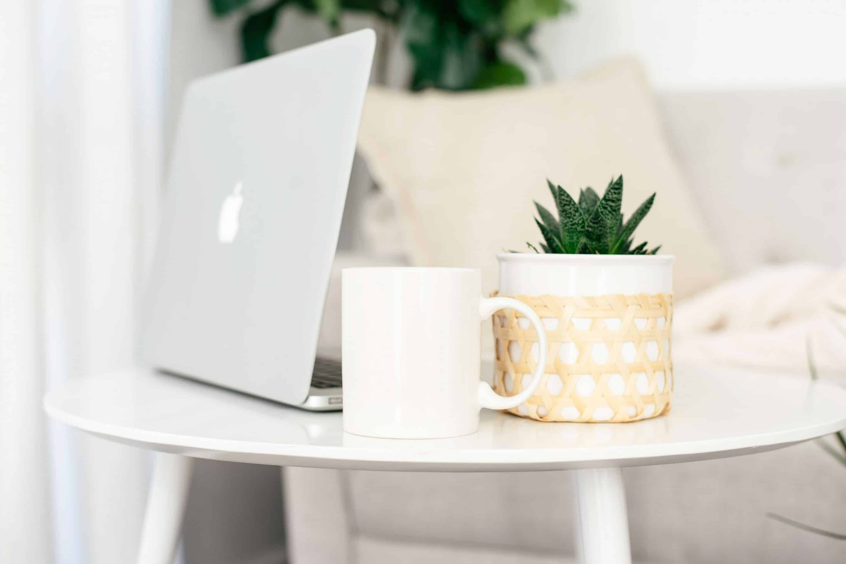 home office desk with mac computer coffee cup and succulent