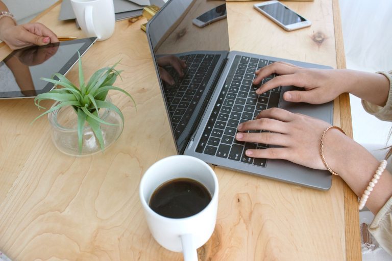 hands on laptop computer with coffee cup