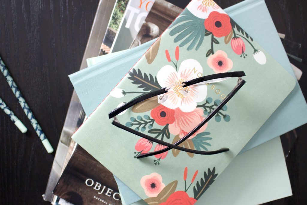 teal floral notebook with reading glasses on home office desk