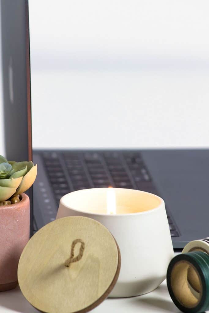 laptop on desk with while candle and succulent plant