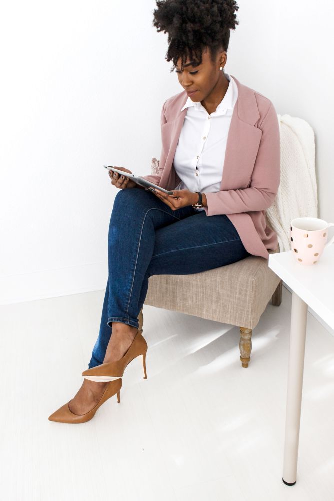 woman in pink blazer and jeans looking at ipad