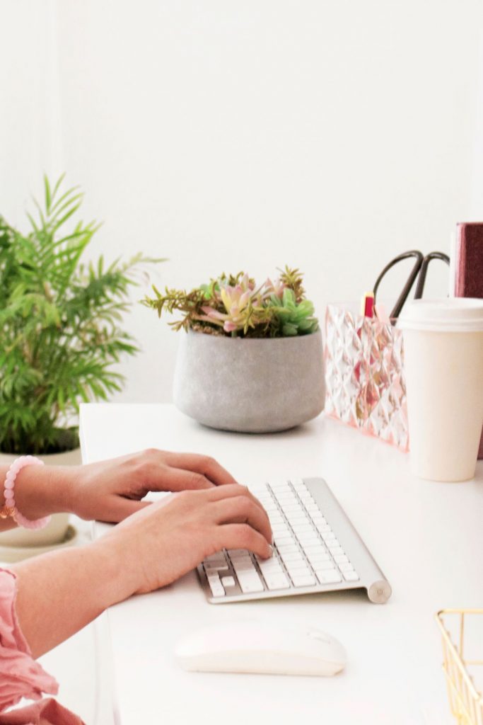 hands on macbook keyboard with coffee cup and succulent
