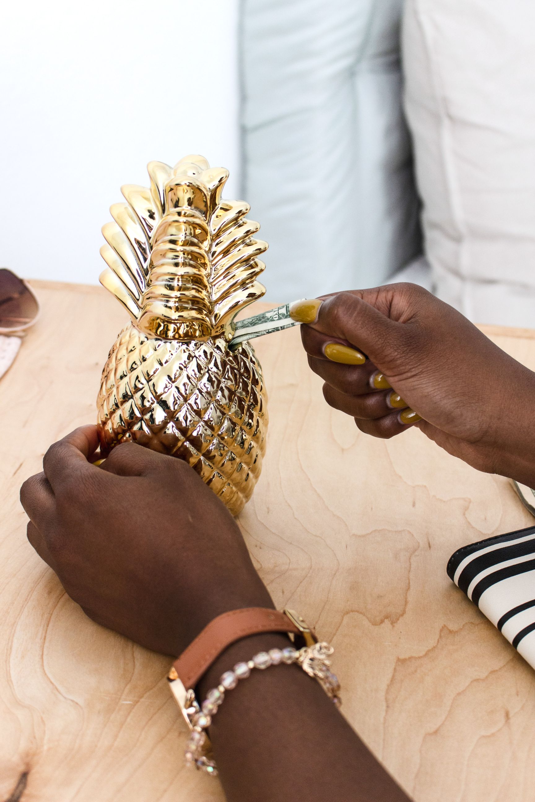 money in the bank as a freelancer hands putting cash into pineapple piggy bank