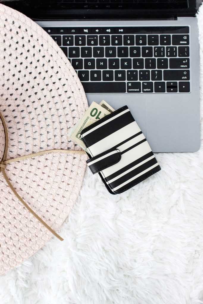 money in wallet with laptop and floppy hat