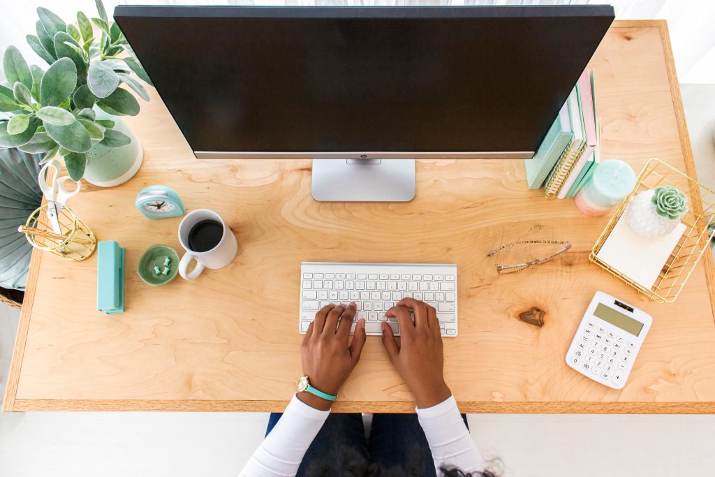 woman's hands typing on keyboard at her styled desk