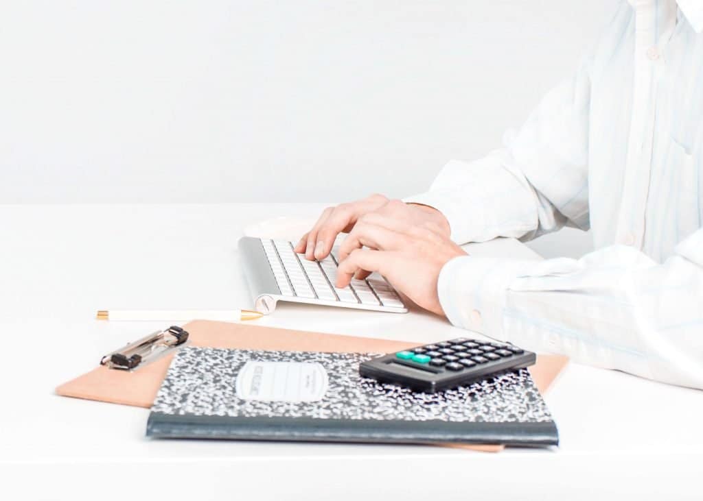hands on keyboard with calculator and notebook
