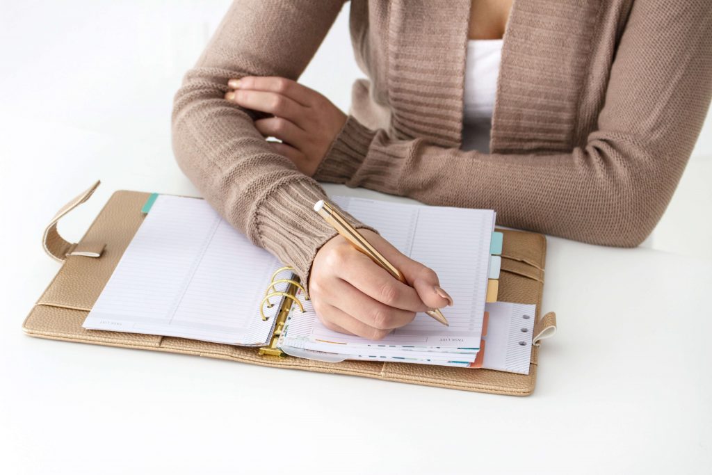 woman in sweater writing in day planner