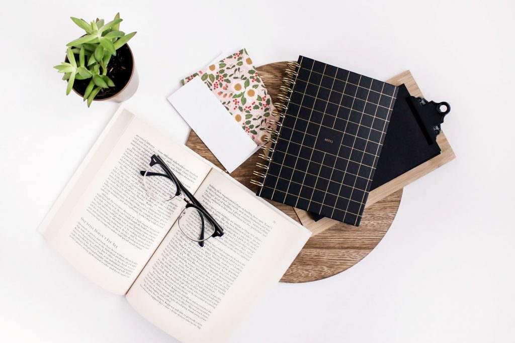 Book glasses and notebook on desk.