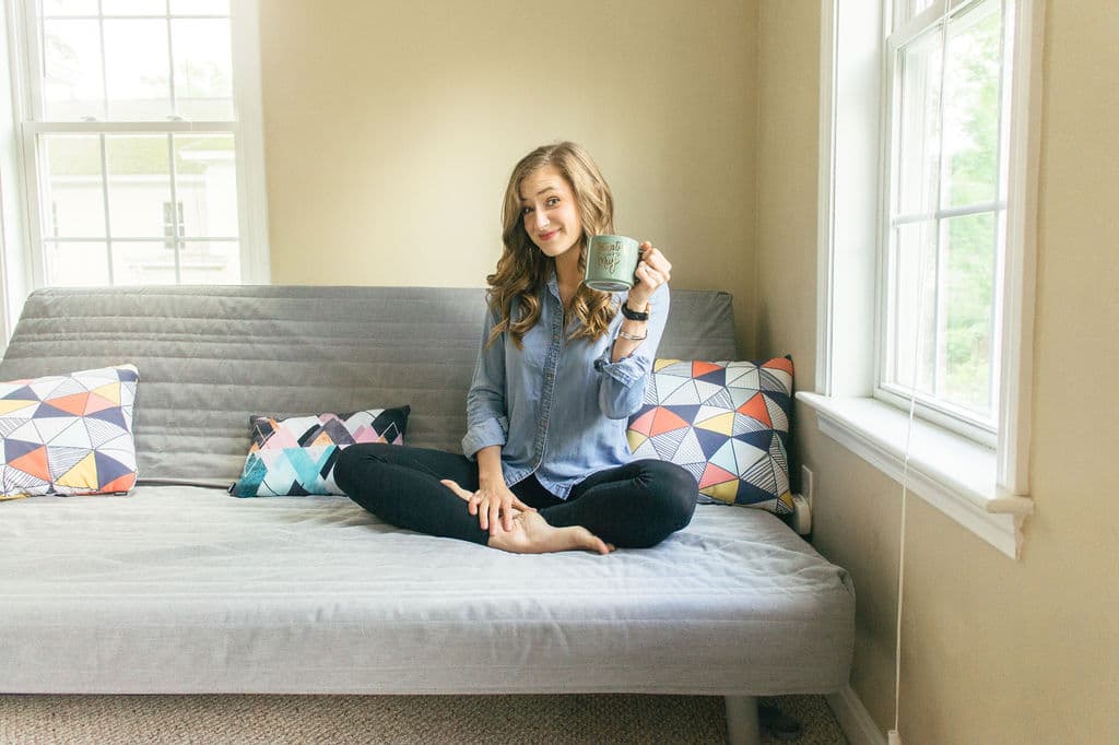 woman sitting on futon holding coffee cup