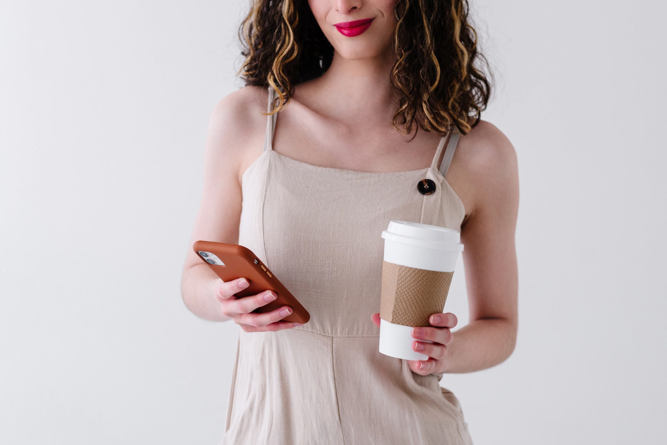 woman holding cell phone and cofee