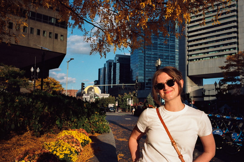 Chynna standing in the street full of fall leaves with her hair up and wearing black sunglasses.