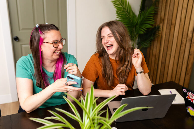 Chynna and Latasha sitting at a dining table working and laughing