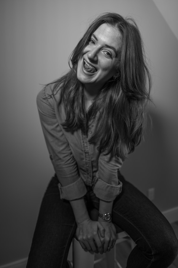 black and white photo of chynna on a stool sticking her tongue out in a funny way