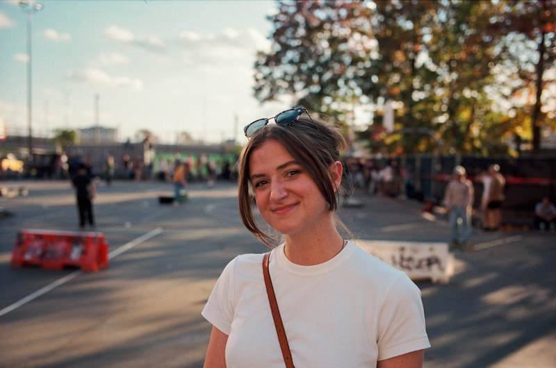 Chynna in the middle of the frame smiling wearing a white tshirt with her hair up standing in the middle of an outdoor basketball park