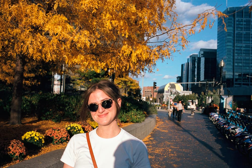 chynna outside in the city wearing sunglasses in front of a yellow leaf fall tree